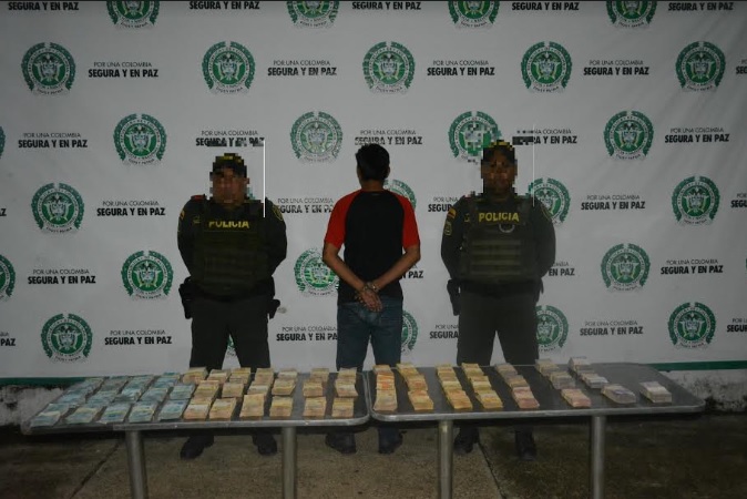 Fue sorprendido cuando transportaba cuantiosa suma de dinero Personas frente a una mesa con reales incautados