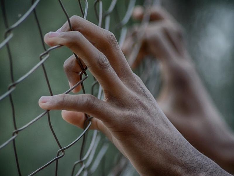 Militares venezolanos detenidos Persona sotenida de un malla mirando a traves de ella