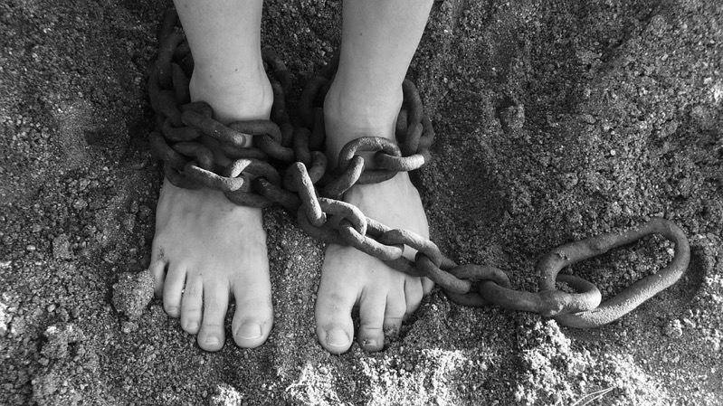 Reclutamiento de menores de edad Persona con pies amarrados con unas cadenas