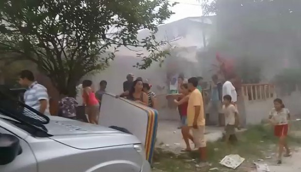Personas a las afuera de una casa incendiada 