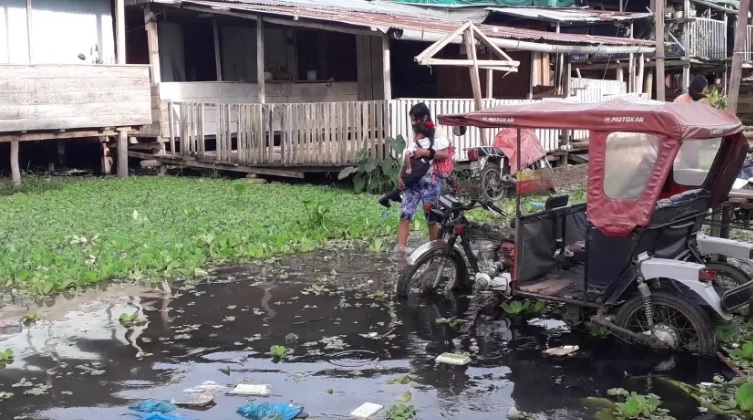 Persona cargando a un niño por el paso de inundaciones 