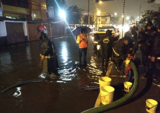 Personal de bomberos drenando alcantarilla 