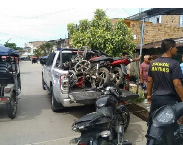 Personas a las afueras de un taller mecanico intervenido por oficiales