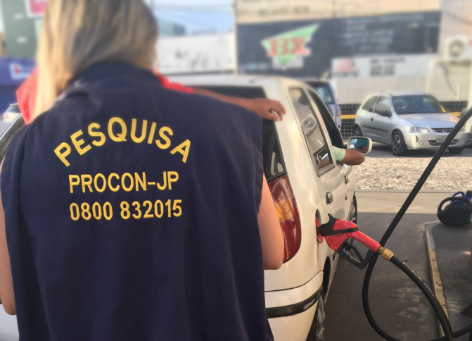 Programa de Proteção e Orientação do Consumidor Mulher ao lado de um posto de gasolina