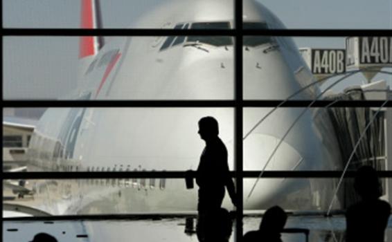 Persona pasando por una ventana en un aeropuerto al lado de avion