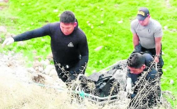 Personas levantando un cadaver del rio