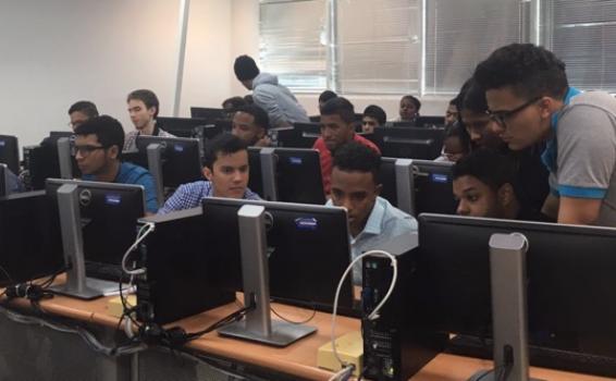 Jovenes en un salon viendo algo en una pantalla de computador