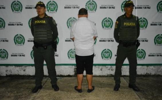 Persona de espaldas y al lado de dos policias en foto