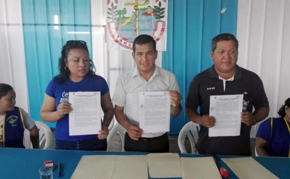 Firma convenio con bomberos en Tamshiyacu Tres personas sosteniendo una hoja