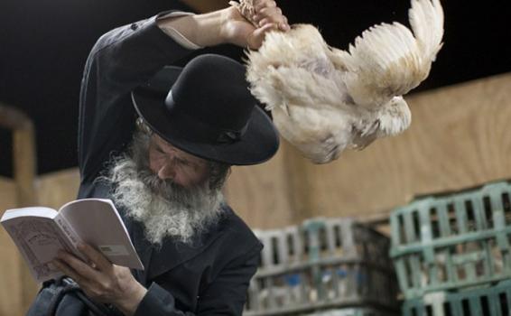 Persona con sombrero con una gallina en la mano en un ritual