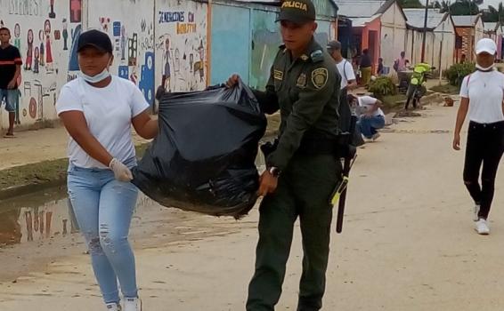 Policia y estudiante llevando una bolsa de basura llena 