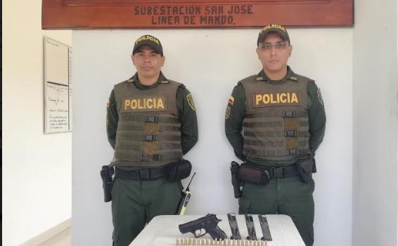 Dos policias frente a una arma de fuego puesta en una mesa