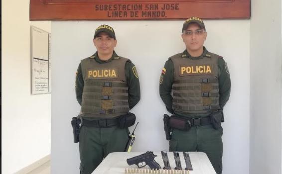Incauta arma de fuego Dos policias frente a una arma de fuego puesta en una mesa