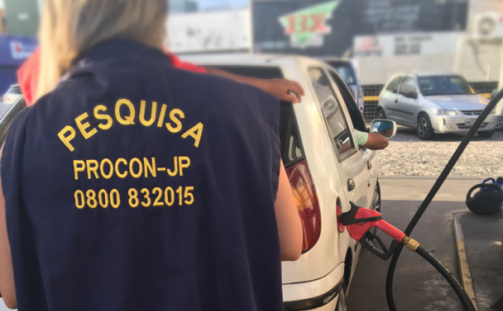 Programa de Proteção e Orientação do Consumidor Mulher ao lado de um posto de gasolina