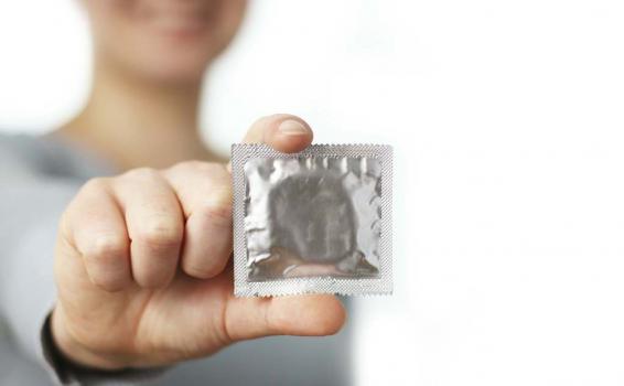 Distribuyen más de 72 millones de preservativos Mujer sosteniendo un preservativo en campañas