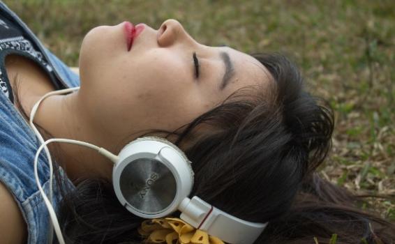 Mujer acostada escuchando musica por audifonos