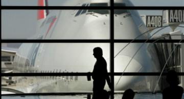 Persona pasando por una ventana en un aeropuerto al lado de avion