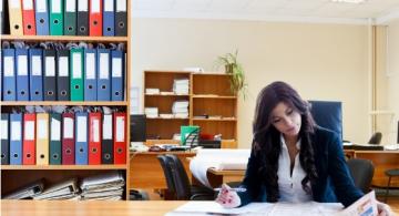 Mujer en un escritorio leyendo un periodico