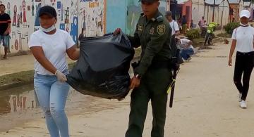 Policia y estudiante llevando una bolsa de basura llena 