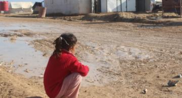 Niña sentada mirando una casa