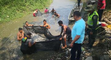 Personas a orillas del rio recogiendo peces