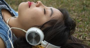 Mujer acostada escuchando musica por audifonos