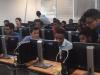 Jovenes en un salon viendo algo en una pantalla de computador